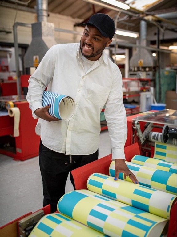 Person in a factory examining colorful printed materials on a machine.