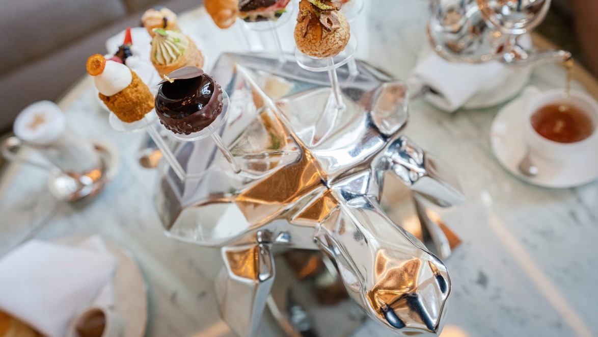 Unique silver turtle centerpiece with assorted gourmet pastries on a marble table at an elegant setting.