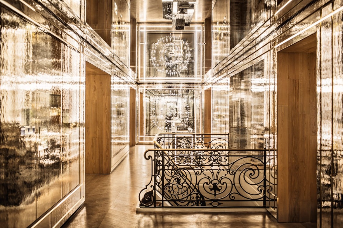 Luxurious hallway with ornate railing, mirrored walls, and warm lighting reflecting an elegant, opulent ambiance.