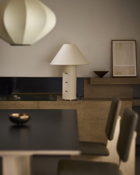 Minimalist dining room with modern furniture, featuring a table, chairs, lamp, wall art, and decorative bowl.
