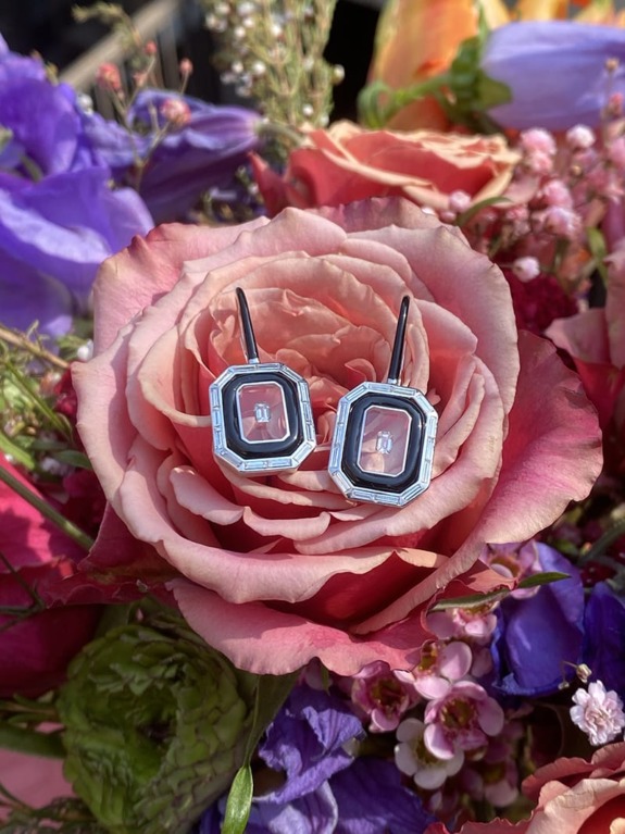 Elegant diamond earrings nestled in a blooming bouquet of colorful roses and flowers.