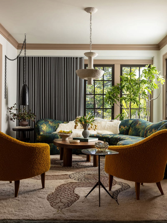 Stylish living room featuring patterned sofa, yellow chairs, round coffee table, large window, and indoor plants.