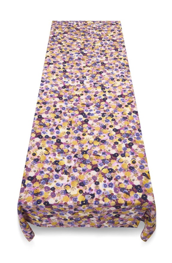 Floral-patterned tablecloth with a mix of purple, yellow, and white flowers covering a rectangular table.