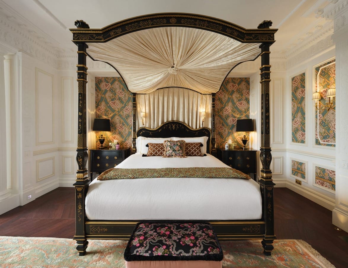 Luxurious bedroom with a canopy bed, ornate wallpaper, and elegant furnishings.