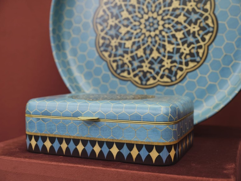 Blue decorative box with gold geometric patterns, placed in front of a matching blue and gold patterned plate.