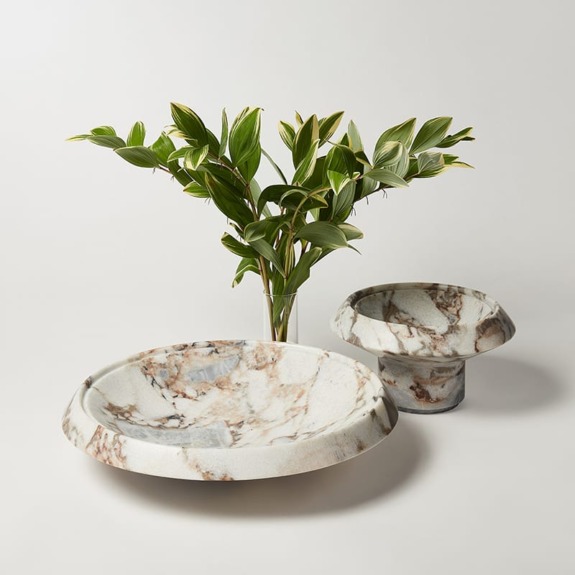 Marble textured bowls with sprig of green leaves in a vase, set against a light background.