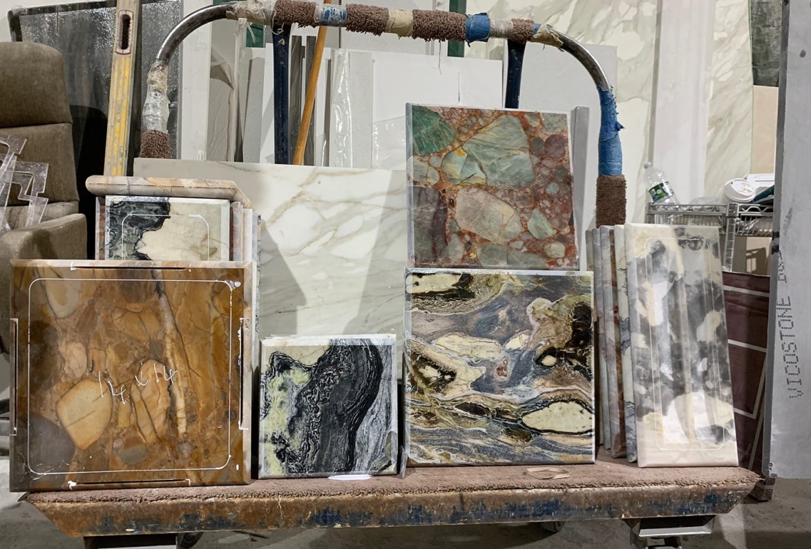 Collection of various stone slabs displayed on a cart, featuring diverse colors and textures in a workshop setting.