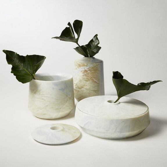 Marble vases with green leaves against a white background.