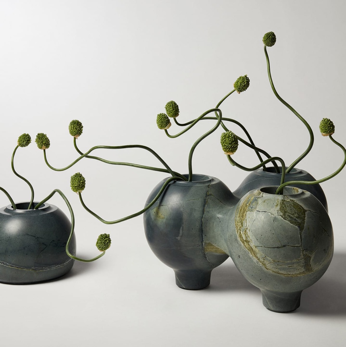 Sculptural ceramic vases with abstract green stems on a light background