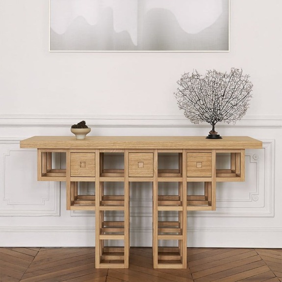 Modern wooden console table with artistic geometric legs, displaying a small tree sculpture and decorative bowl.