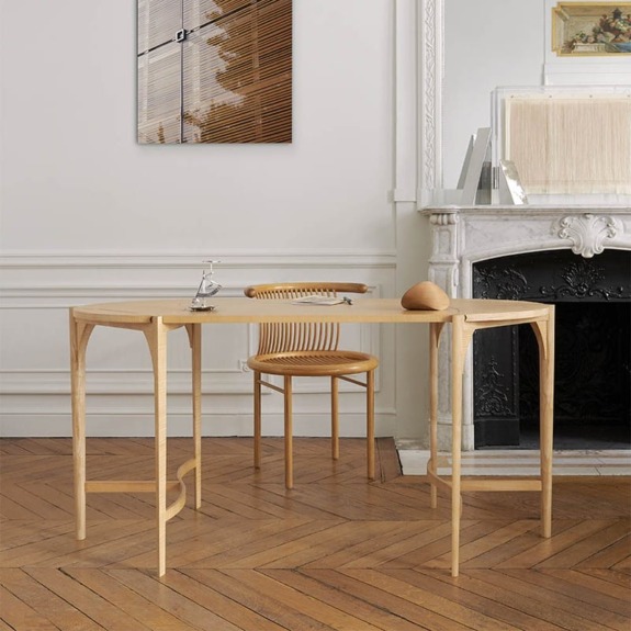 Minimalist wooden table and chair set in a stylish room with herringbone wood flooring and a white fireplace.