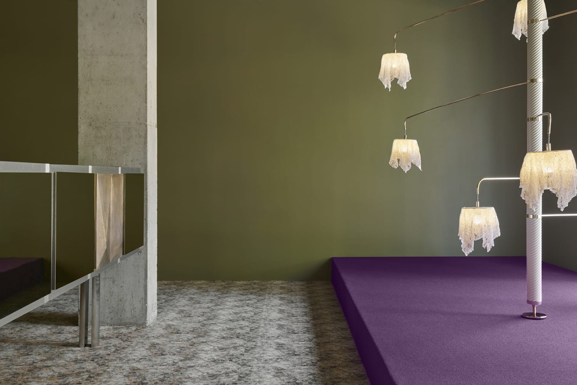 Modern interior with unique hanging light fixture, purple platform, and green walls, featuring a concrete column and railing.