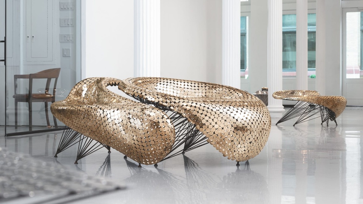Futuristic gold seating with intricate metallic design in a modern lobby with large windows and white pillars.