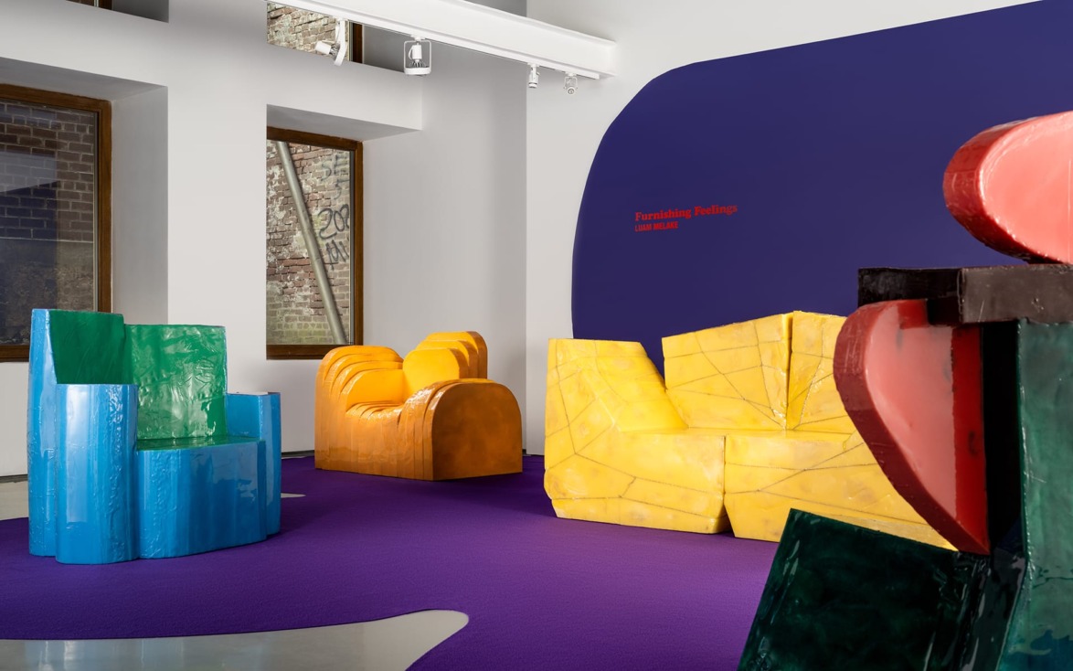 Colorful, abstract furniture pieces in a modern gallery with a purple floor and bright walls.