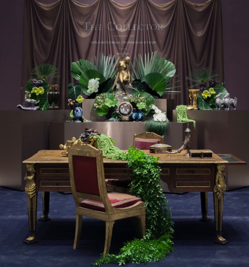 Luxurious antique desk with ornate decorations, green foliage, and elegantly arranged plants on display.