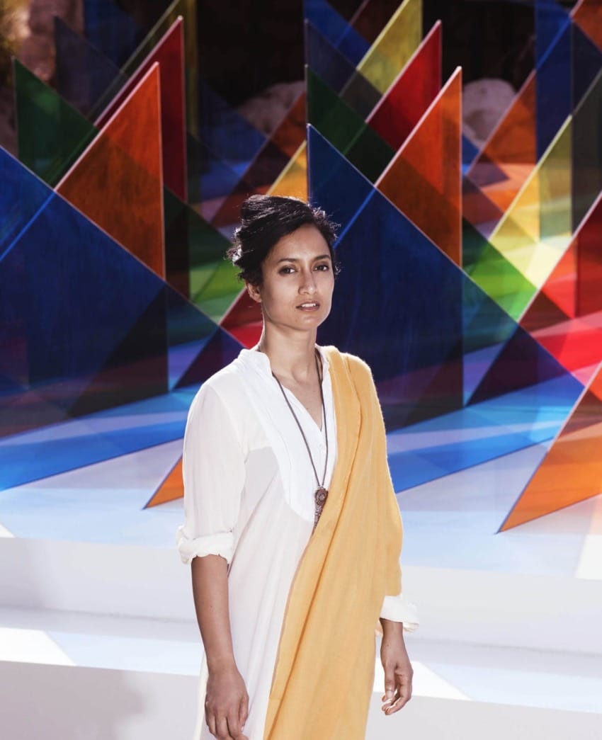Person standing in front of vibrant geometric art installation with colorful triangular panes.