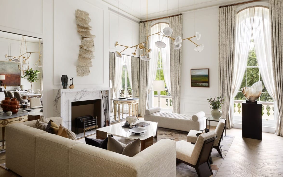 Elegant living room with modern decor, large windows, a marble fireplace, and a beige sectional sofa.