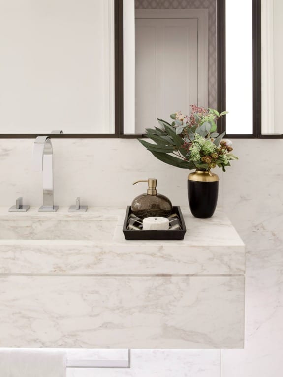 Modern bathroom sink with marble countertop, sleek faucet, decorative plant, and soap tray, reflecting minimalist design.