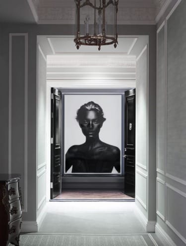 Hallway with ornate moldings leading to a large black and white portrait of a person on the far wall.