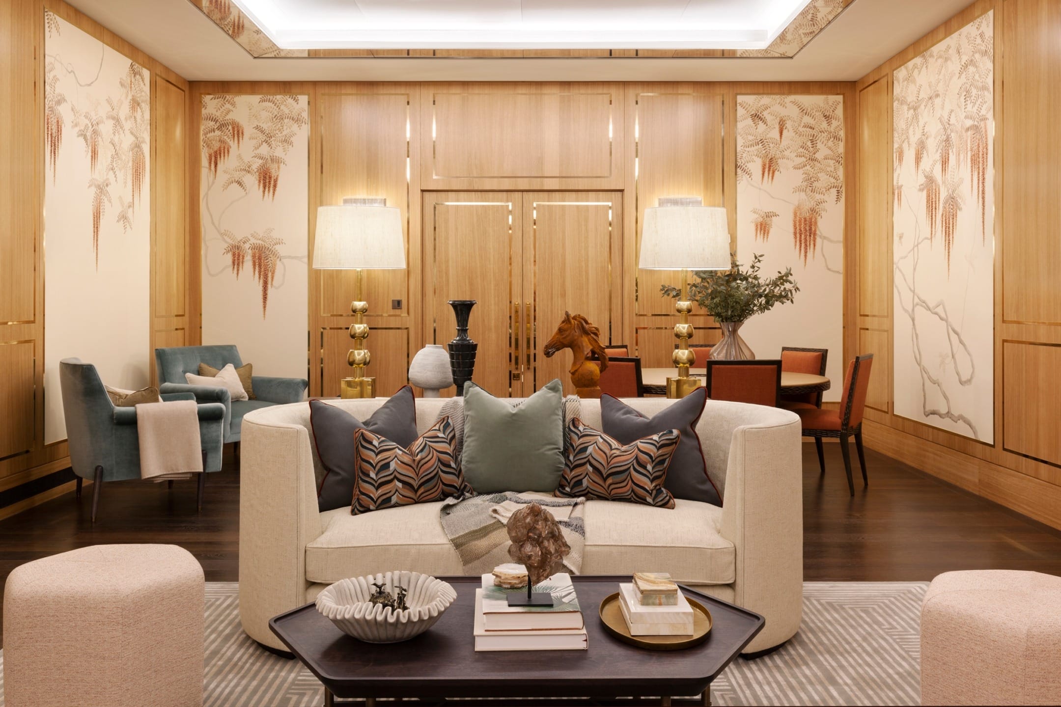 Luxurious living room with modern furniture, decorative pillows on a curved sofa, and artistic wall designs.