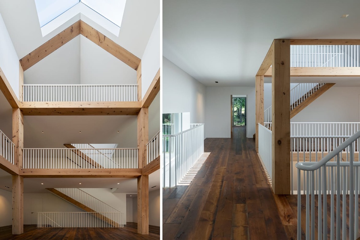 Spacious modern interior with wooden beams, white walls, high ceilings, and a wooden staircase with natural light from skylight.