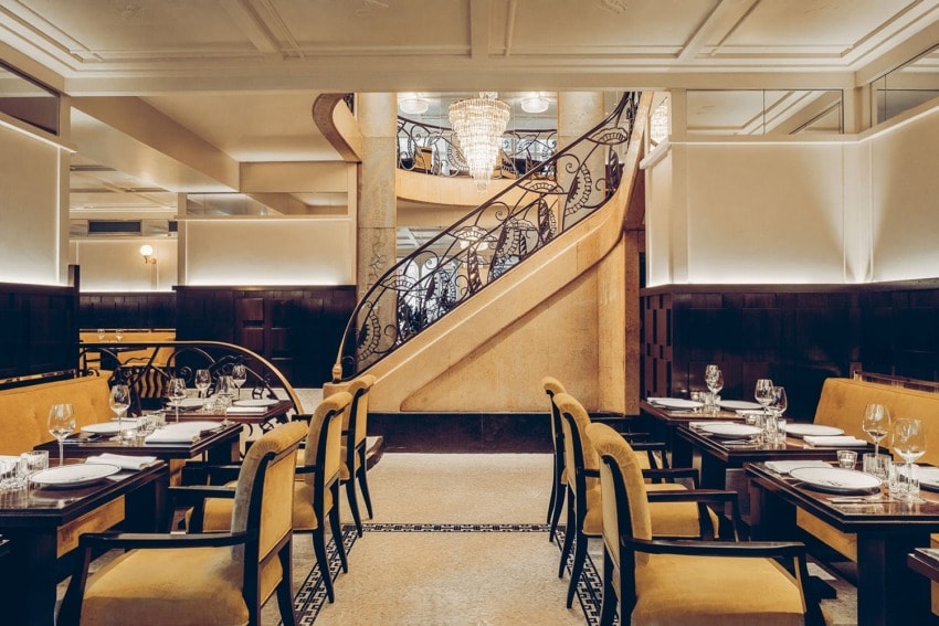 Elegant restaurant interior with a spiral staircase, set tables, and warm lighting.