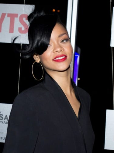 A person with hoop earrings and red lipstick smiling at a public event.