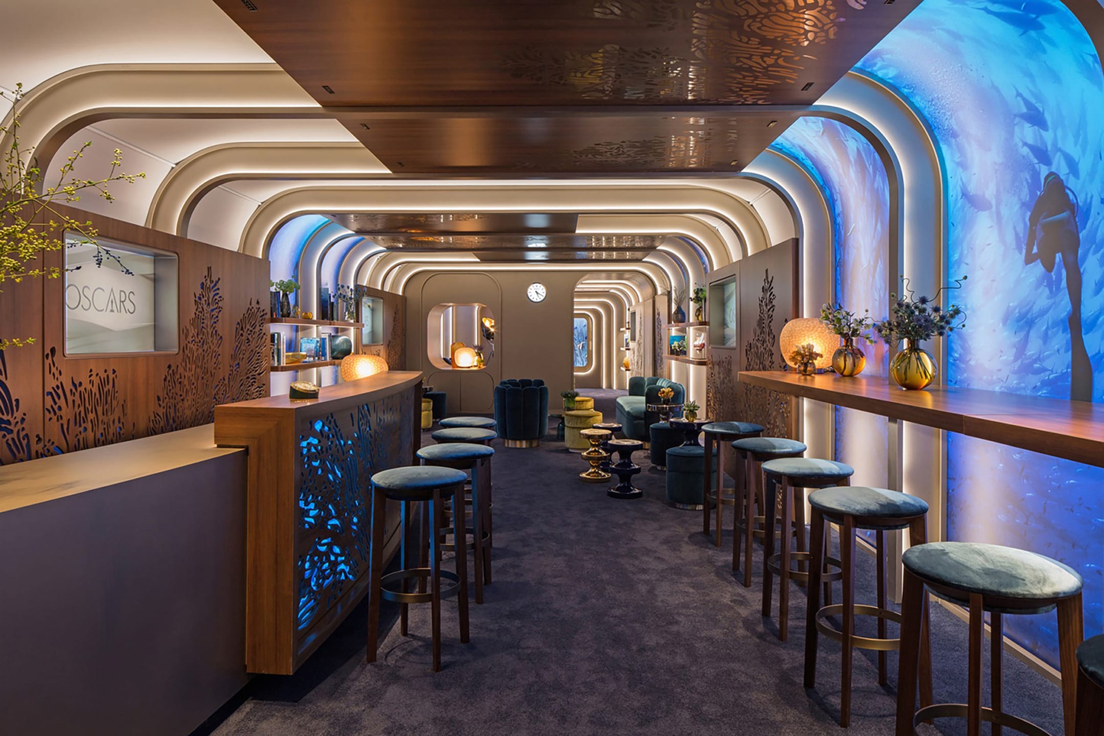 Stylish modern bar with wooden counters, high stools, and decorative lighting in an elegant, arched interior space.