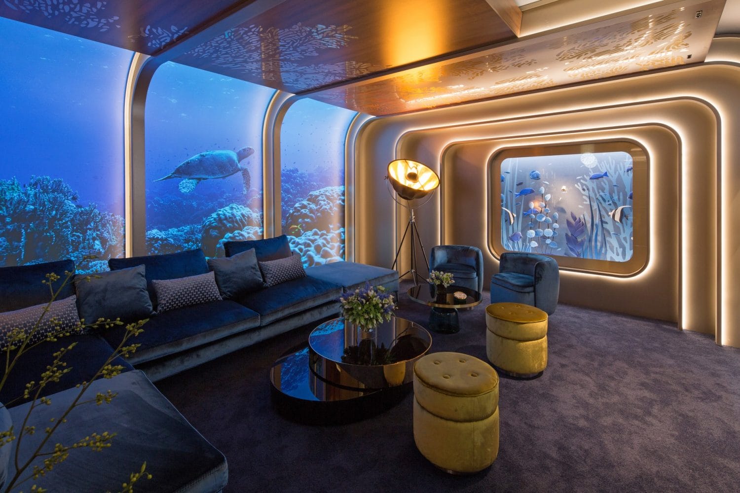 Luxurious underwater-themed living room with large aquarium-like windows and modern, comfortable seating arrangements.