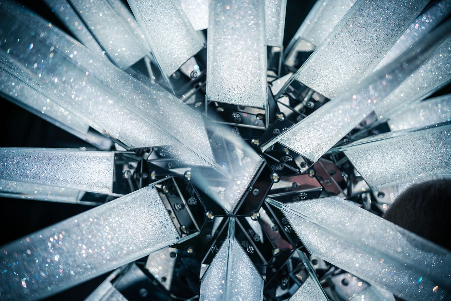 Close-up view of geometric crystal-like structures reflecting light, forming a star pattern with metallic accents.