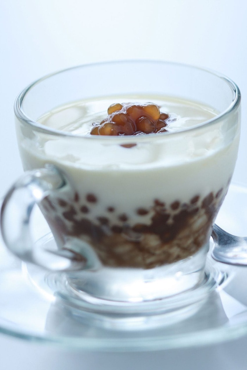 Glass mug of creamy dessert with brown tapioca pearls on top.