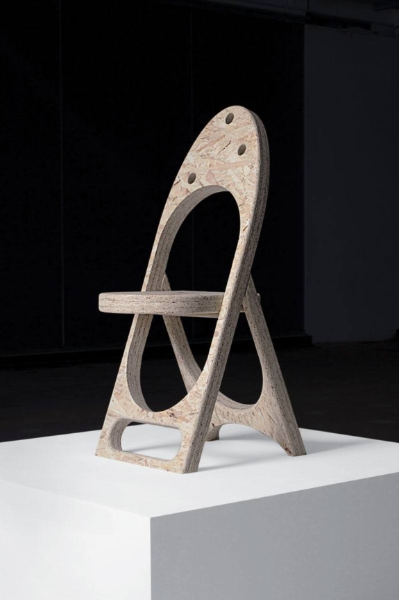 Unique sculptural chair on display in a dimly lit gallery.