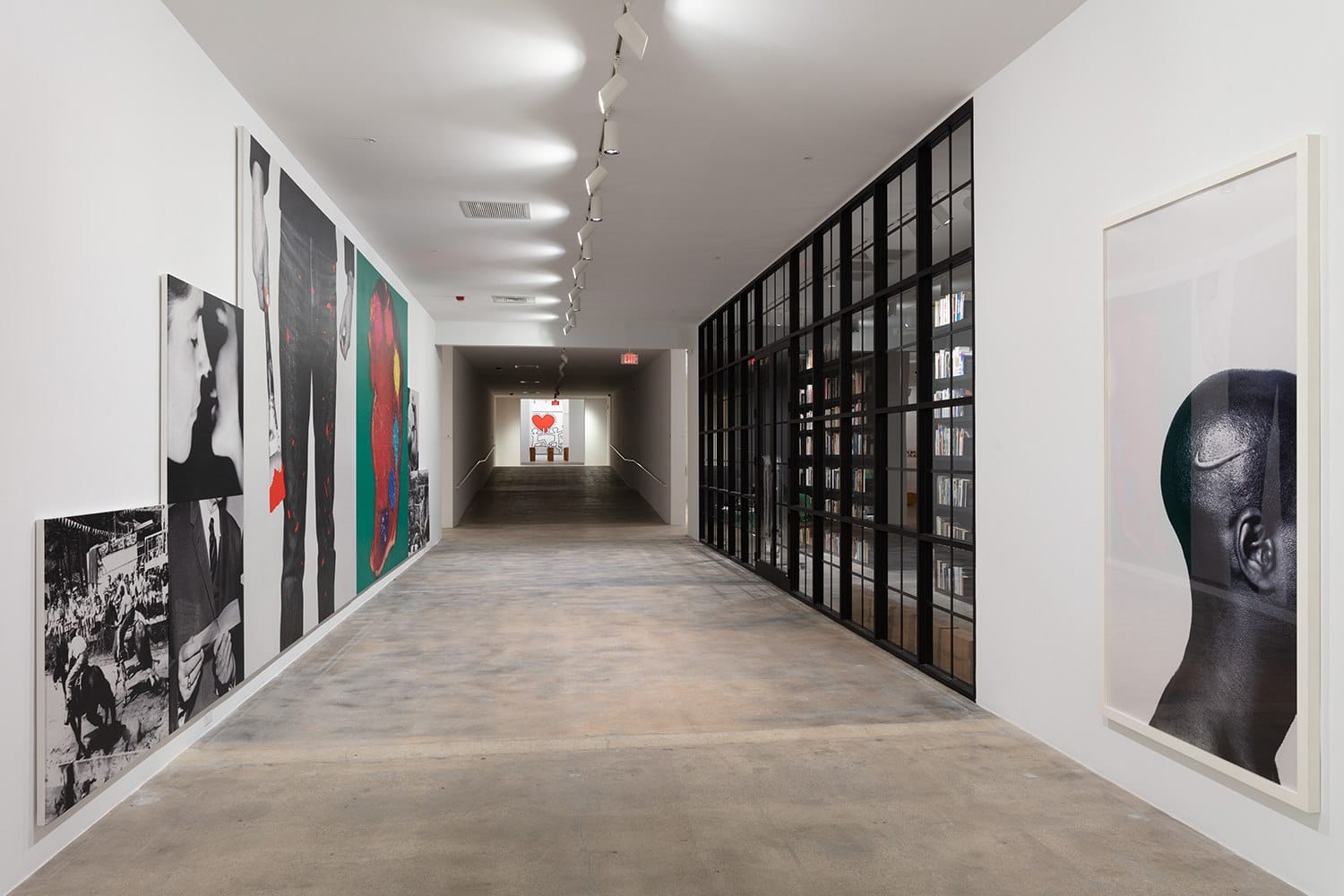 Art gallery hallway with modern paintings on walls and a distant artwork under spotlight.