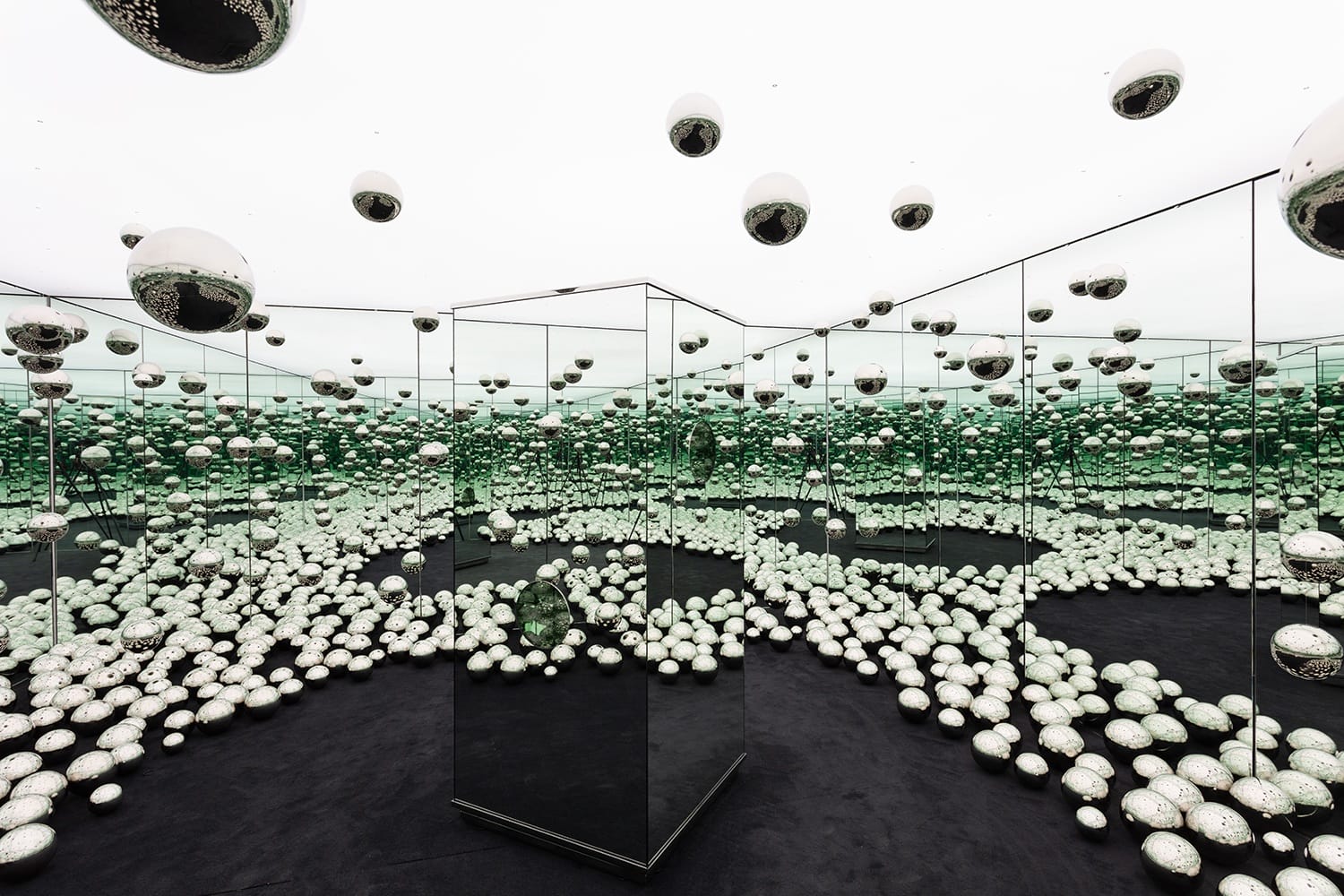 Mirror room filled with reflective spheres creating an infinite pattern of repetition and optical illusion.