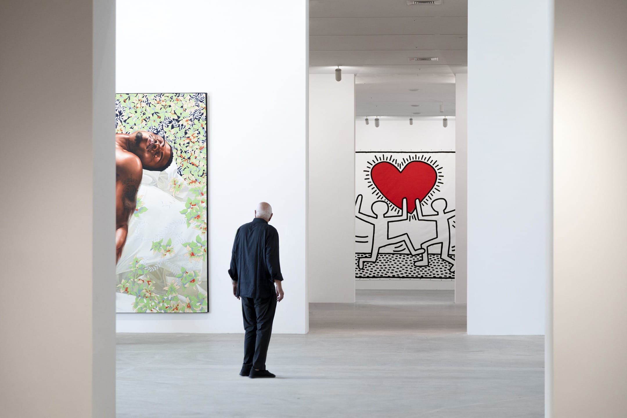 Person viewing colorful contemporary art in a modern gallery with white walls and diverse paintings.