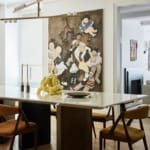 Modern dining room with a white table, contemporary chairs, abstract chandelier, and a large painting of children on the wall.