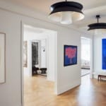 Contemporary art gallery with wooden floors, modern lighting, and vividly colored paintings on the walls.