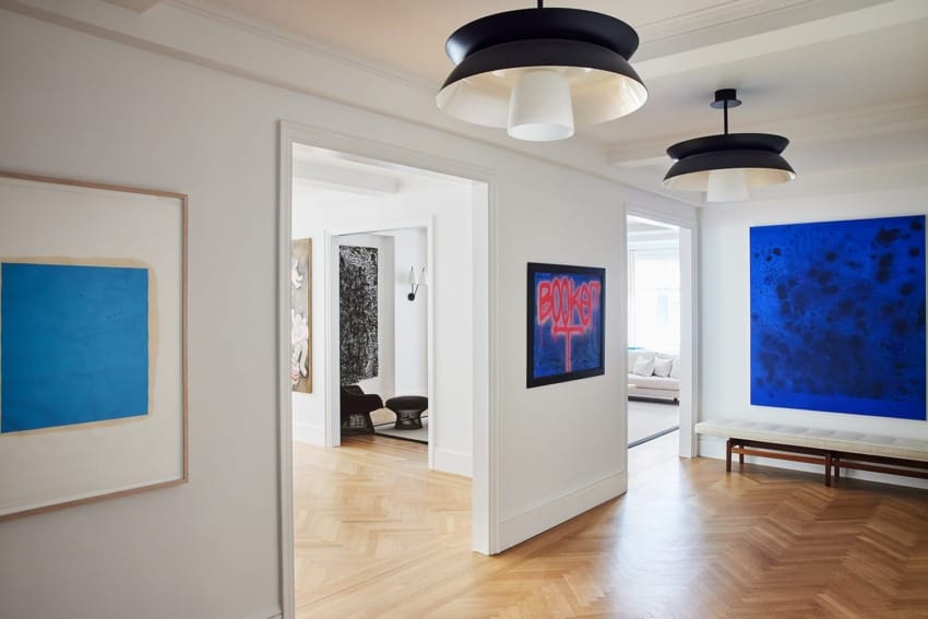 Contemporary art gallery with wooden floors, modern lighting, and vividly colored paintings on the walls.