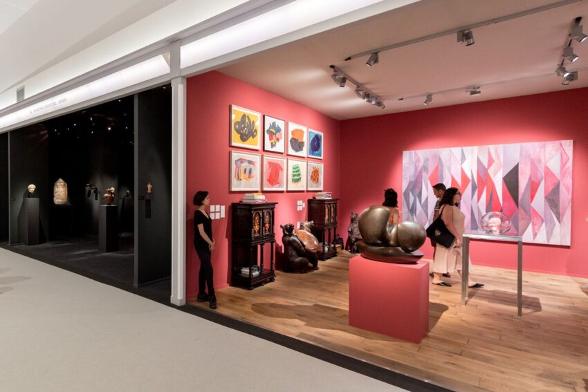 People viewing artwork in a modern gallery with colorful paintings and sculptures on display.