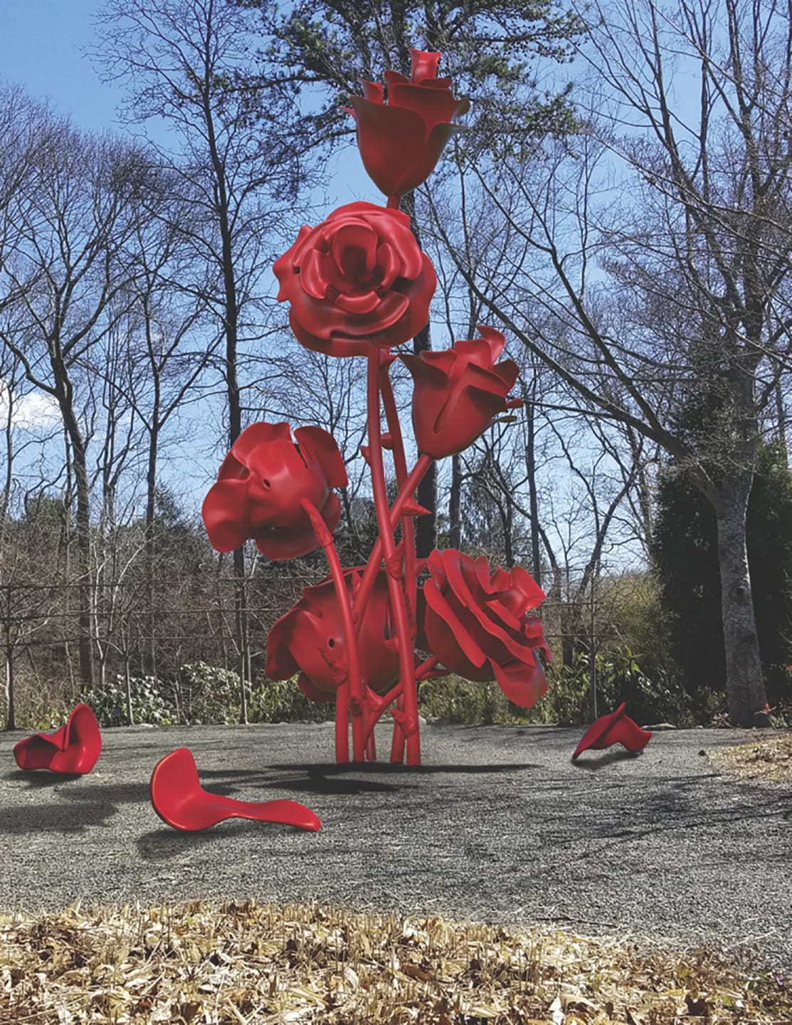 Tall red rose sculpture in a park setting with bare trees in the background and fallen petals on the ground.