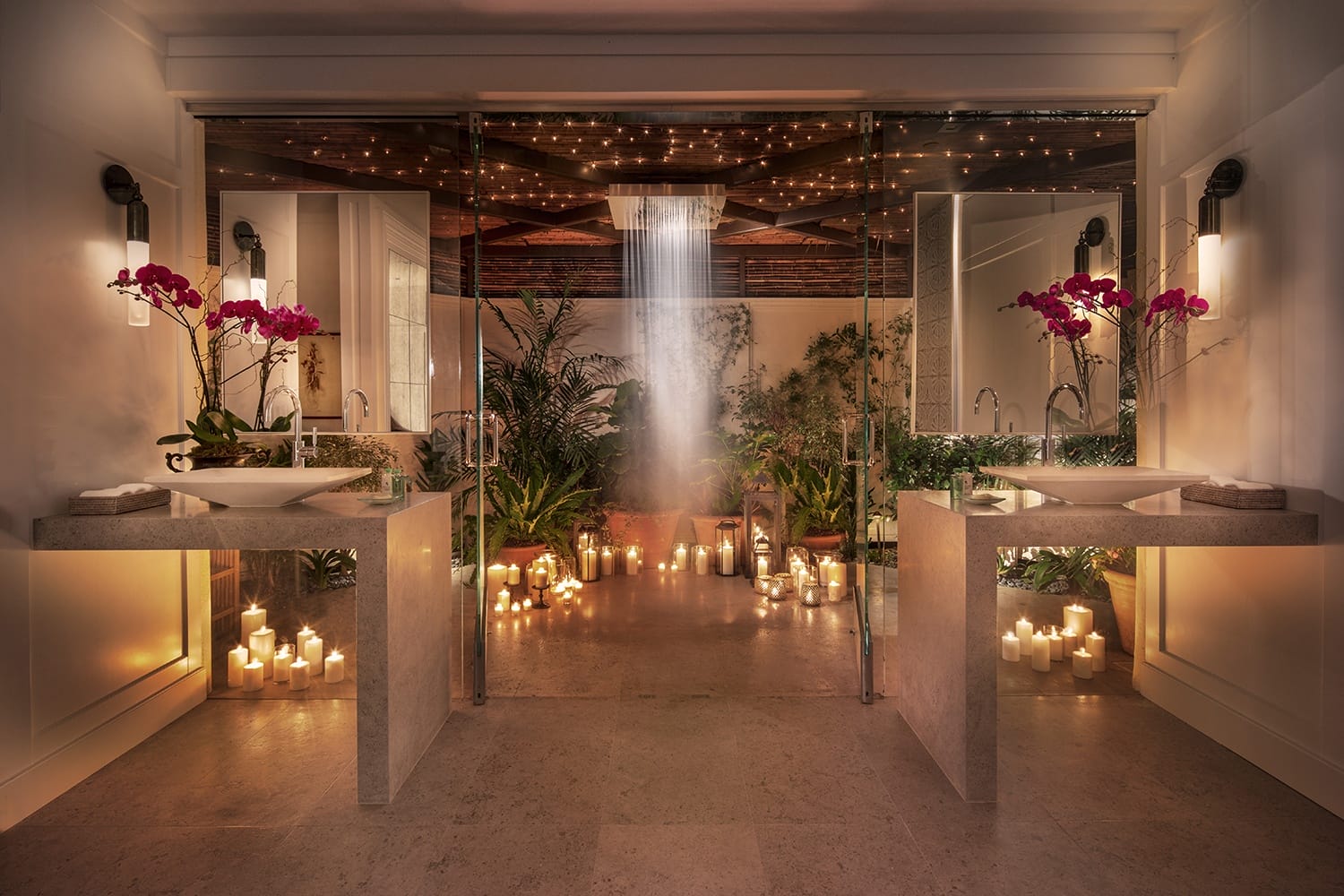 Luxurious bathroom with candles, orchids, and a waterfall shower creates a serene spa-like atmosphere.