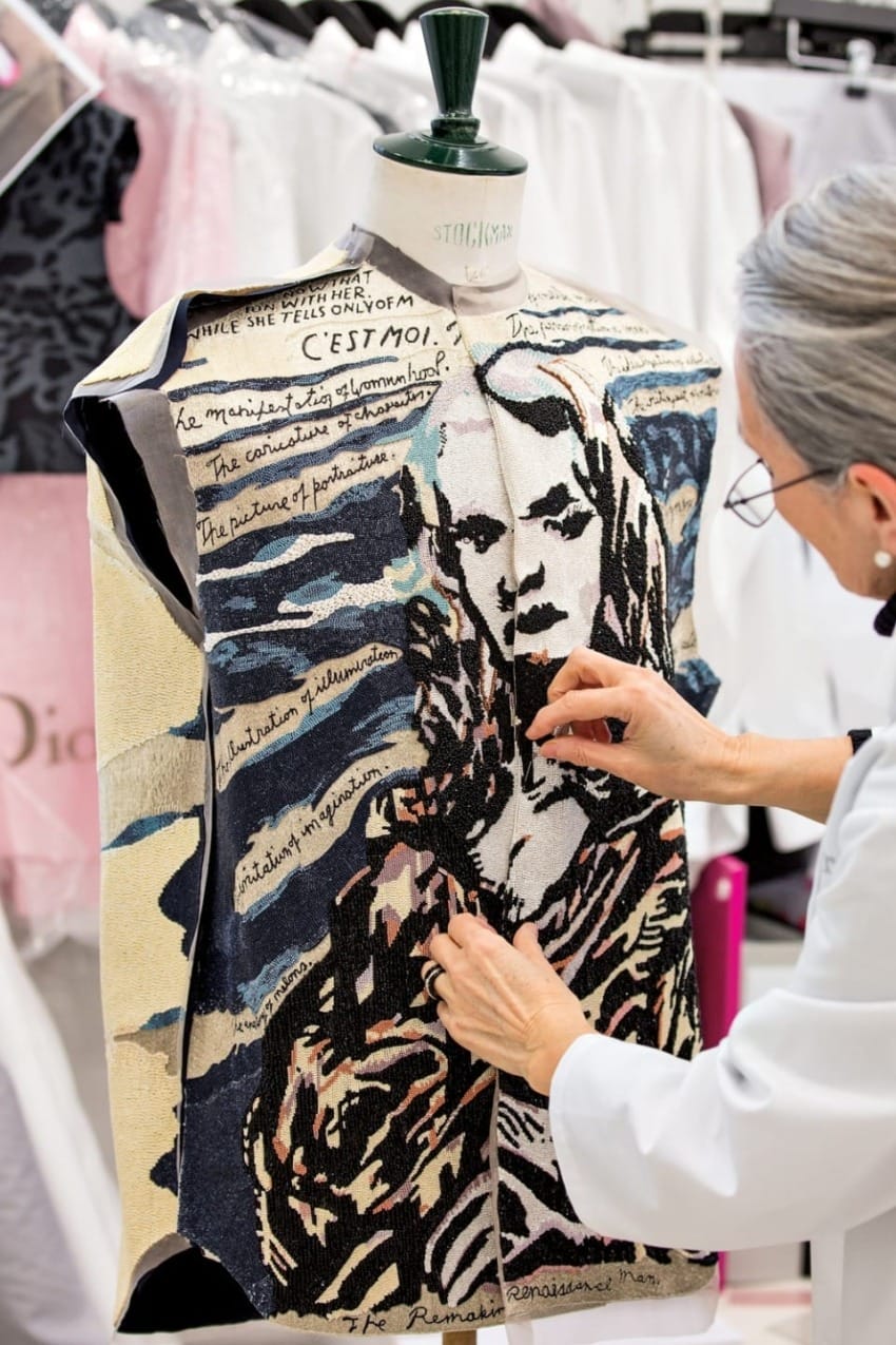 Person working on a mannequin with a unique fabric displaying a stylized design and handwritten text.