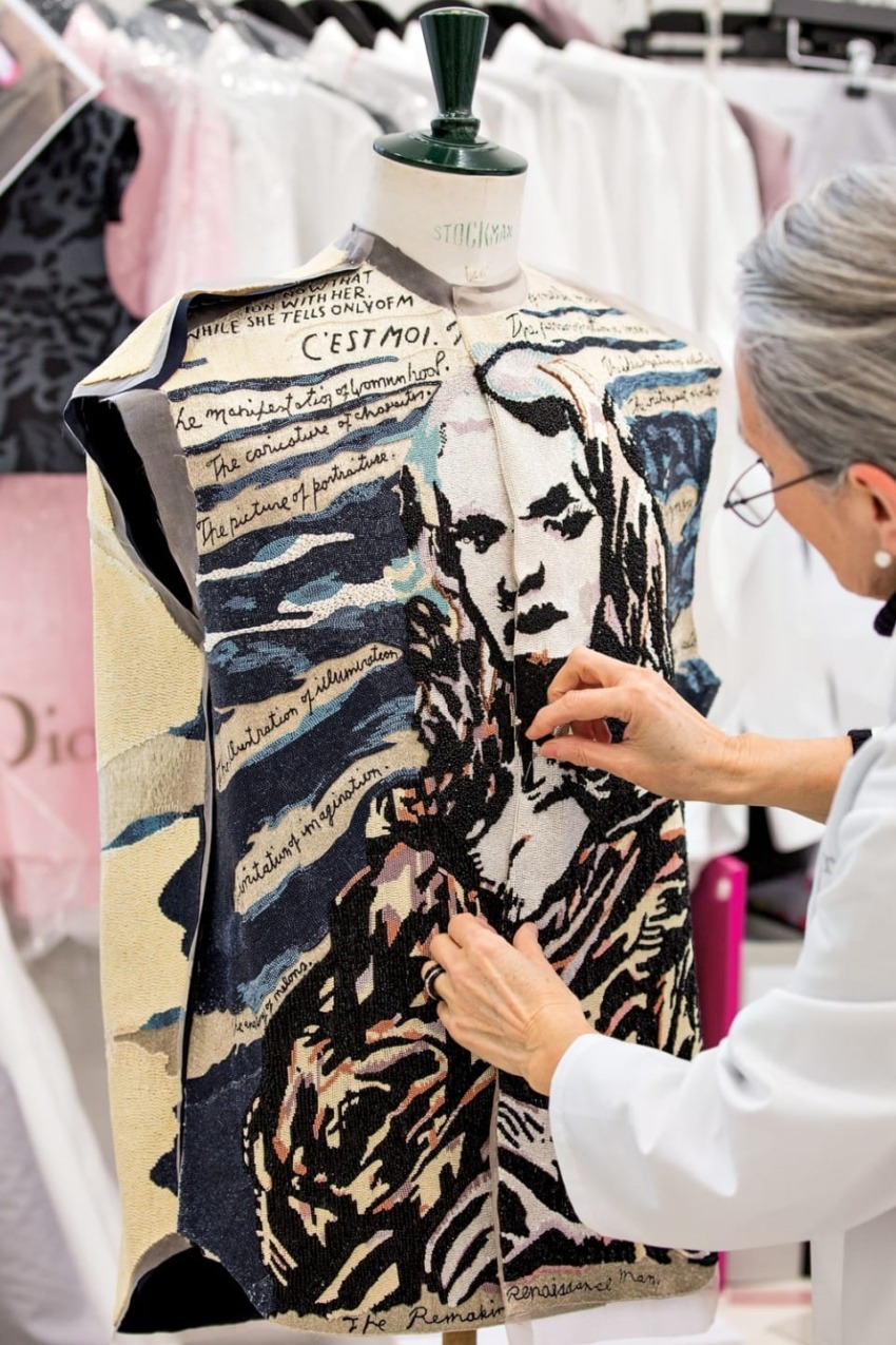 Person working on a mannequin with a unique fabric displaying a stylized design and handwritten text.