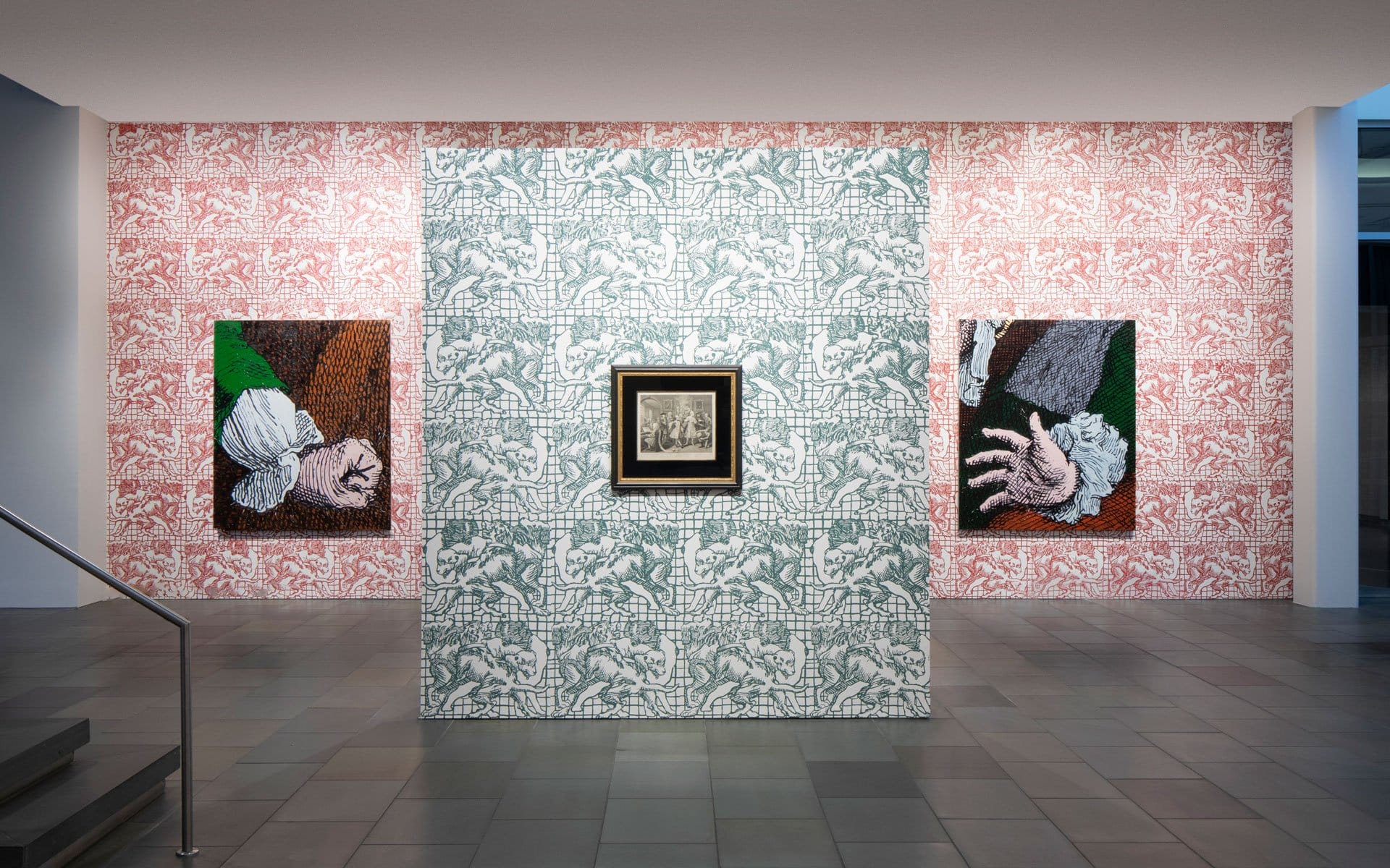 Art exhibit featuring two hand-themed paintings on patterned walls and a framed central artwork in a modern gallery setting.
