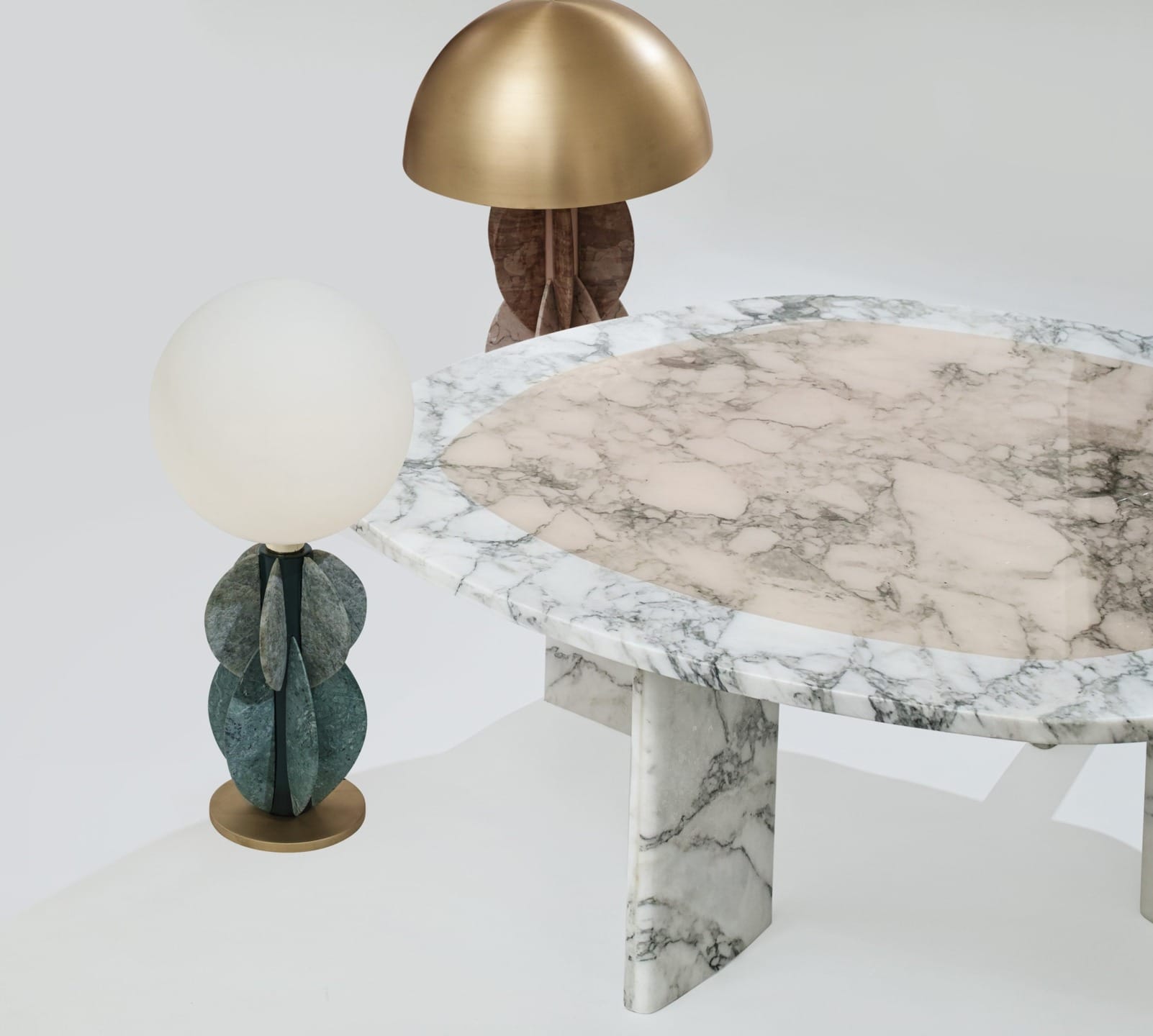 Oval marble table with two unique stone and brass lamps on a white background.