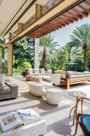 Open-air living room with modern furniture and palm trees, blending natural and contemporary elements for a relaxing atmosphere