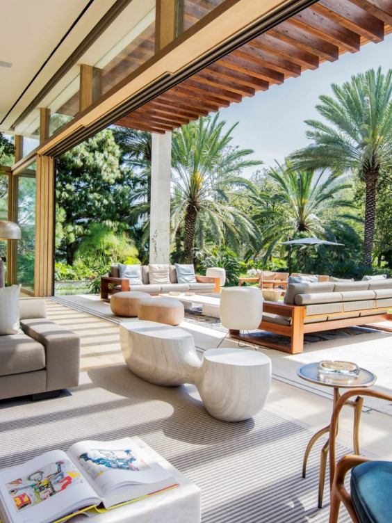 Open-air living room with modern furniture and palm trees, blending natural and contemporary elements for a relaxing atmosphere