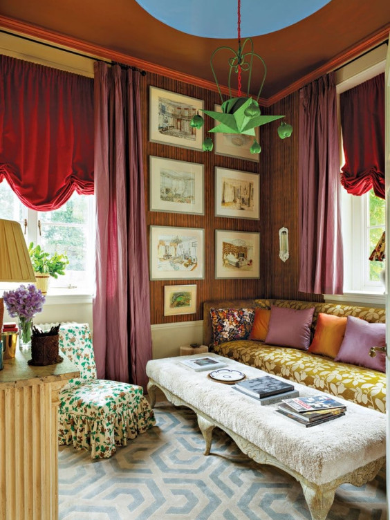 Cozy living room with colorful curtains, wall art, patterned furniture, and a unique green chandelier.