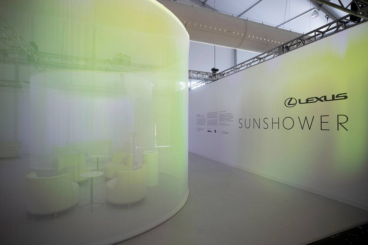 Modern exhibition space with a circular seating area and Sunshower logo on the wall.