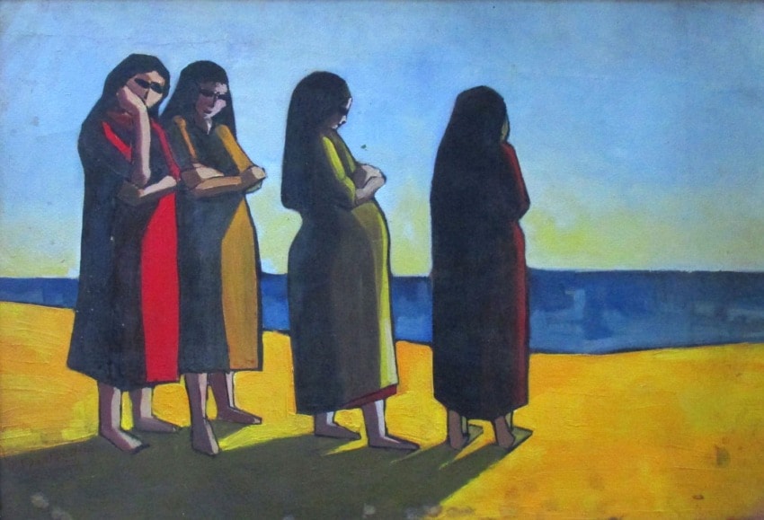 Four women in long dresses standing on a beach, gazing at the ocean under a bright sky.